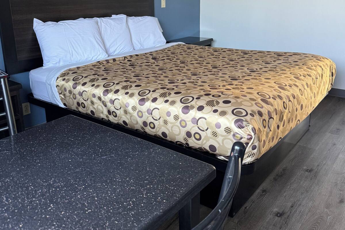 A hotel room with a bed, a small table, and a chair.