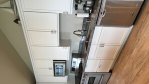 A modern kitchen with white cabinets, stainless steel appliances, and a wooden floor. - Alaska SeaScape Lodge (Kenai)