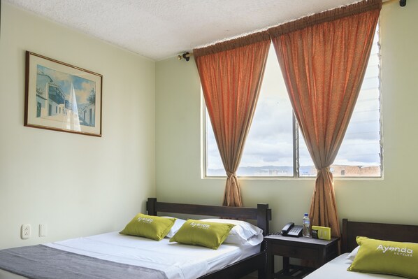 A hotel room with a bed, two pillows, a nightstand, a phone, a bottle, and a painting on the wall. - Ayenda 1506 La Puerta del Sol (Bucaramanga)