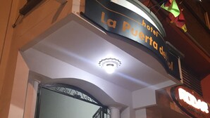 The entrance of La Puerta del Sol hotel with a staircase leading up to the entrance, a wrought iron gate, and a sign above the door.