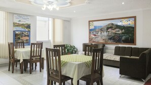 A dining area with a table set for four, surrounded by wooden chairs. There is a sofa against the wall and a large framed picture above it.