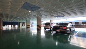 A parking garage with two cars parked, a blue curtain, and a patterned ceiling.