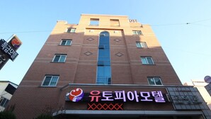 A tall brick building with a sign for 'Udo Hotel' and a heart symbol.