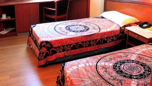 Quarto de hotel com duas camas, uma mesa e uma cadeira.