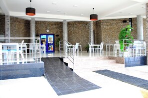 A spacious lobby with a stone wall, a reception desk, and a staircase leading to upper floors. - MindelHotel (Mindelo)