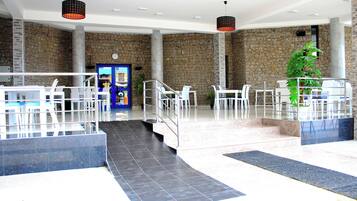 Eine geräumige Lobby mit Steinwand, einer Rezeption und einer Treppe zu den oberen Etagen.