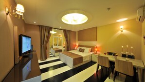 A hotel room with a bed, bedside tables, a desk, and a television.