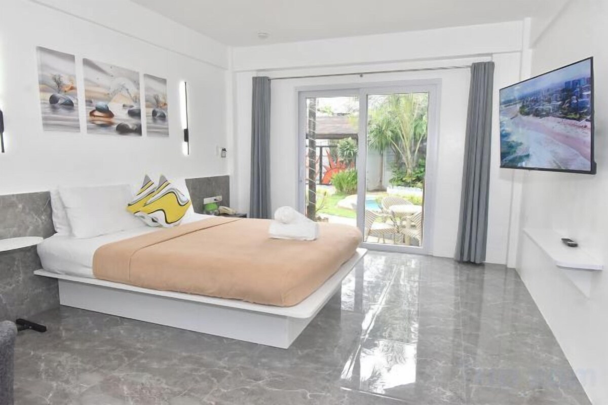 A modern hotel room with a bed, a television, and a view of the outdoors.