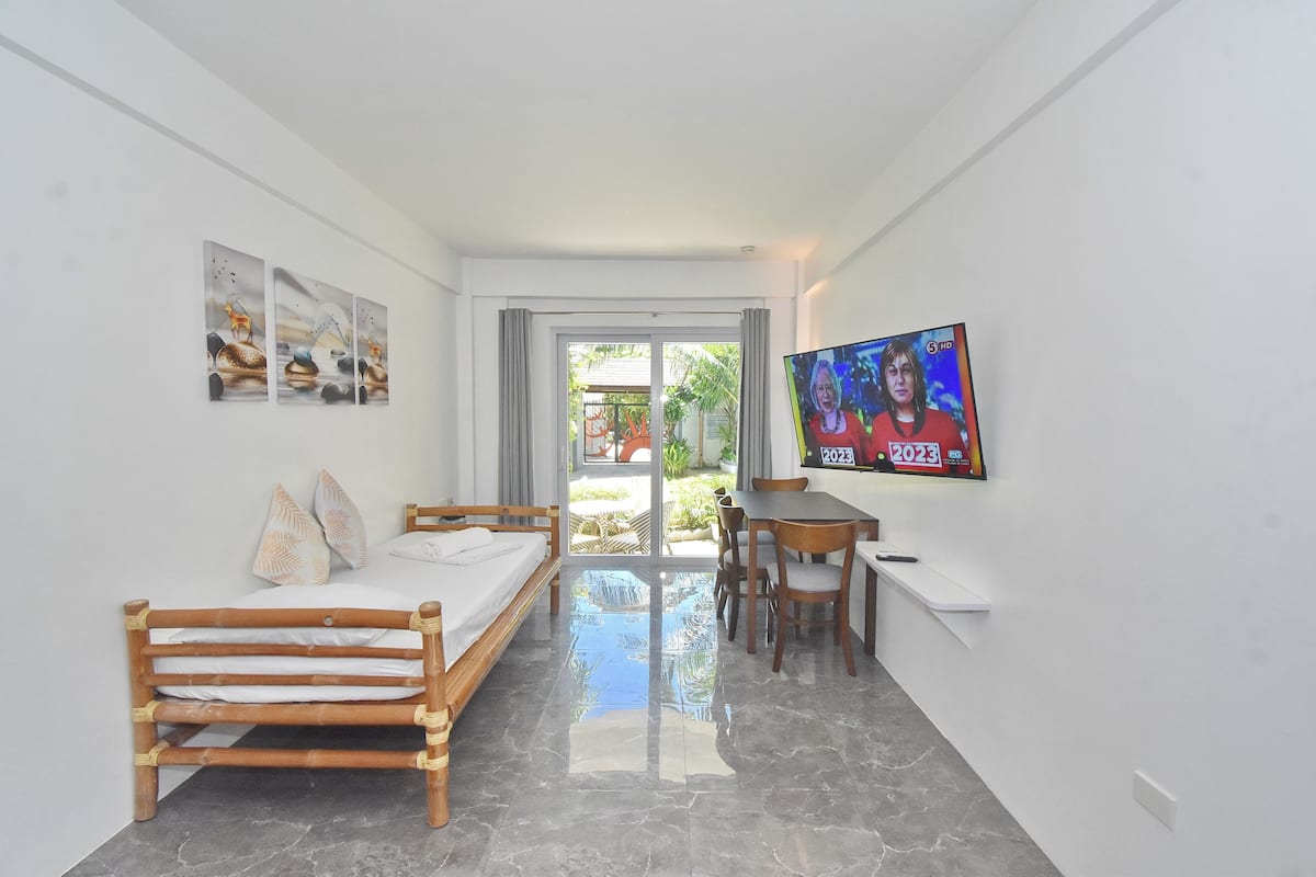 Una habitación moderna con una cama, un escritorio y un televisor.