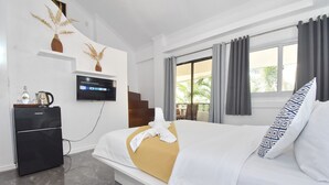 Habitación de hotel con cama, televisor, minibar y vistas al exterior.