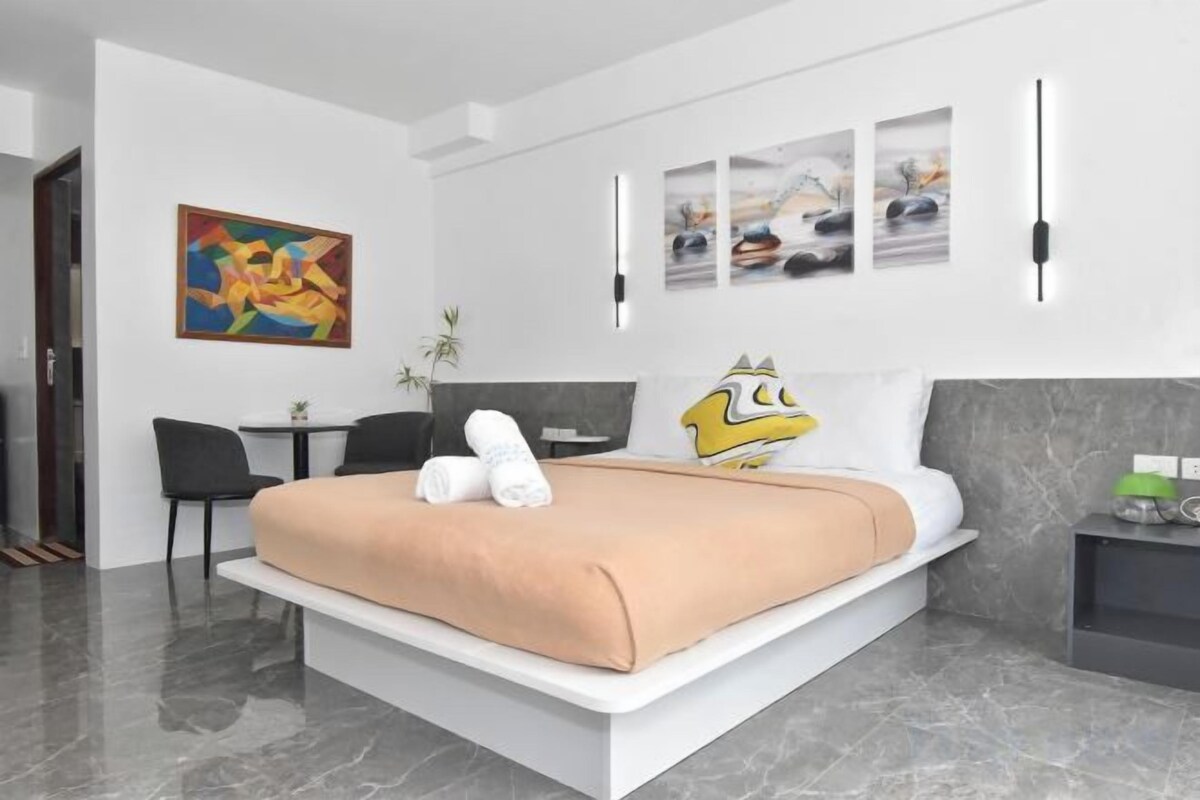 Une chambre d’hôtel moderne, dotée d’un grand lit, d’un bureau et d’une chaise.