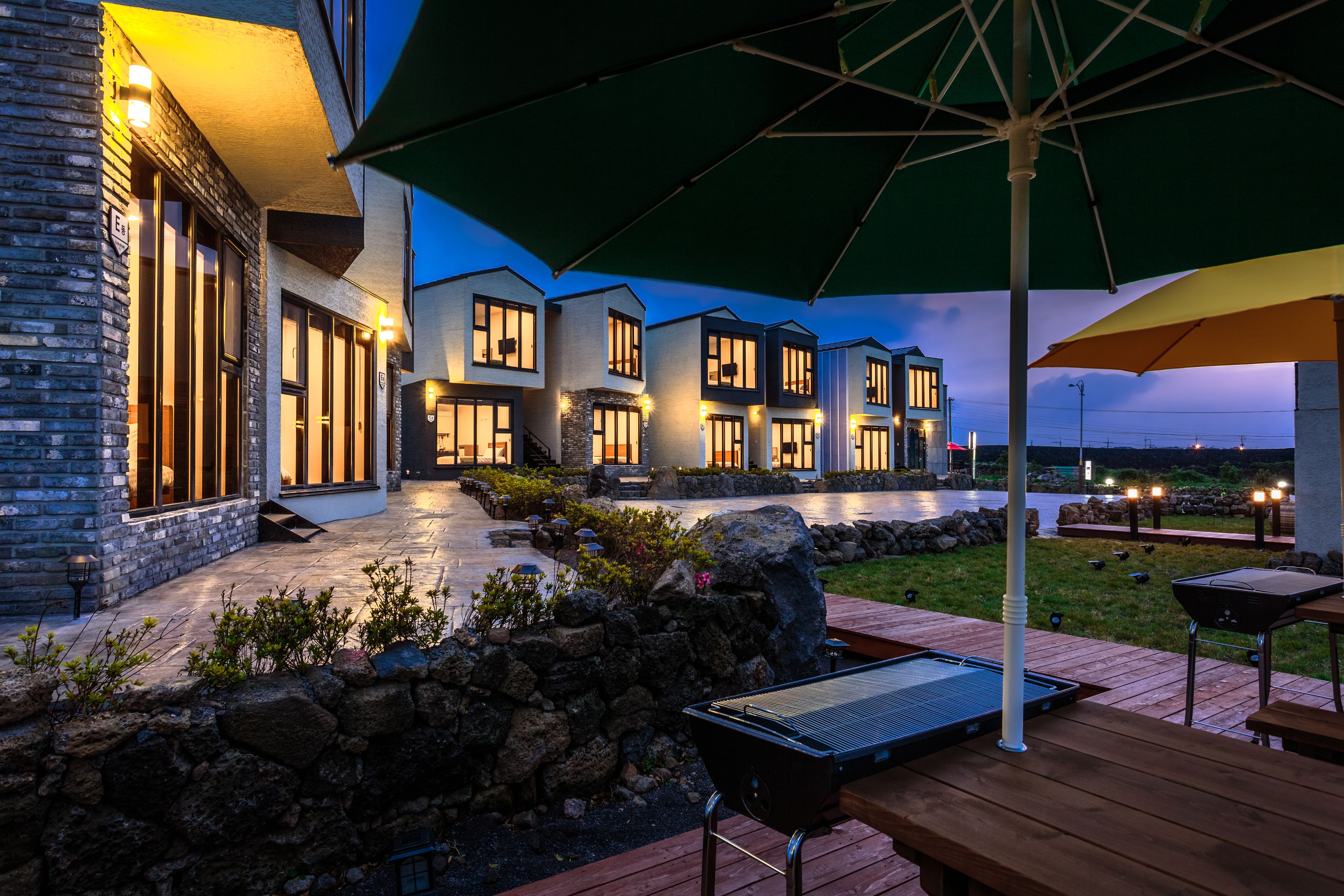 Un patio exterior moderno con muros de piedra, suelo de madera y mobiliario para exteriores.