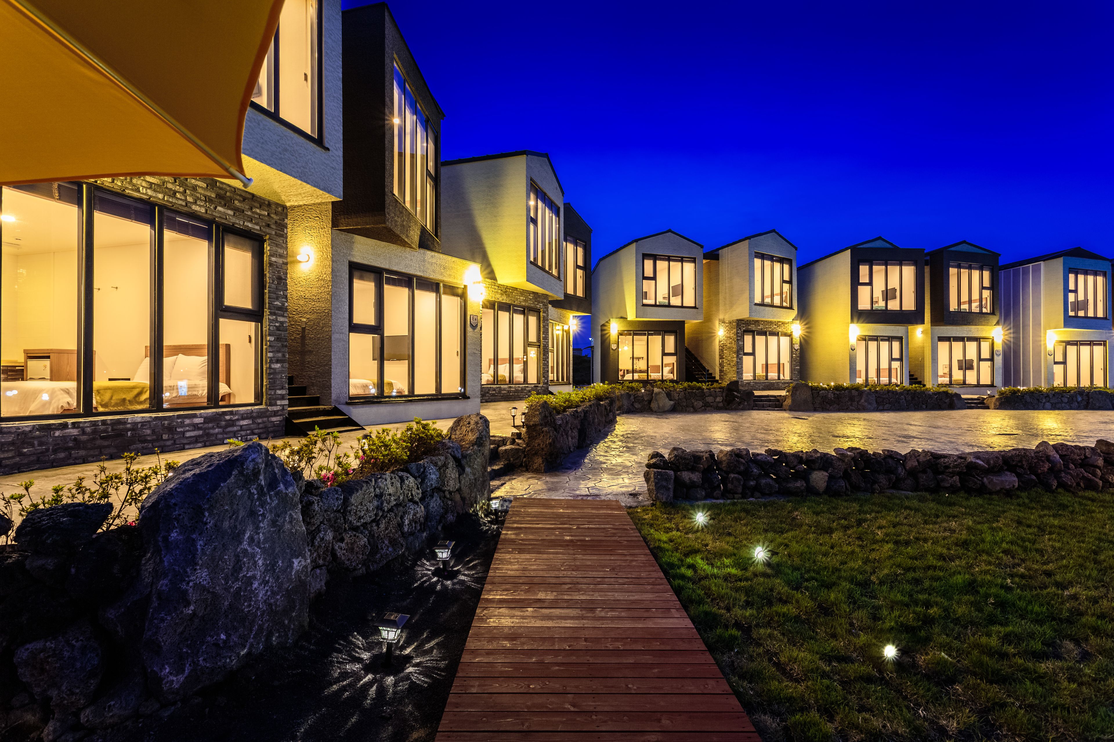 A modern hotel with multiple units, a wooden pathway, and a landscaped area with rocks and plants.