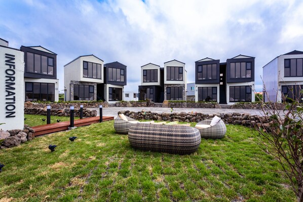 Un ensemble immobilier moderne comprenant plusieurs logements, des espaces de détente en plein air et un chemin pavé de pierres.