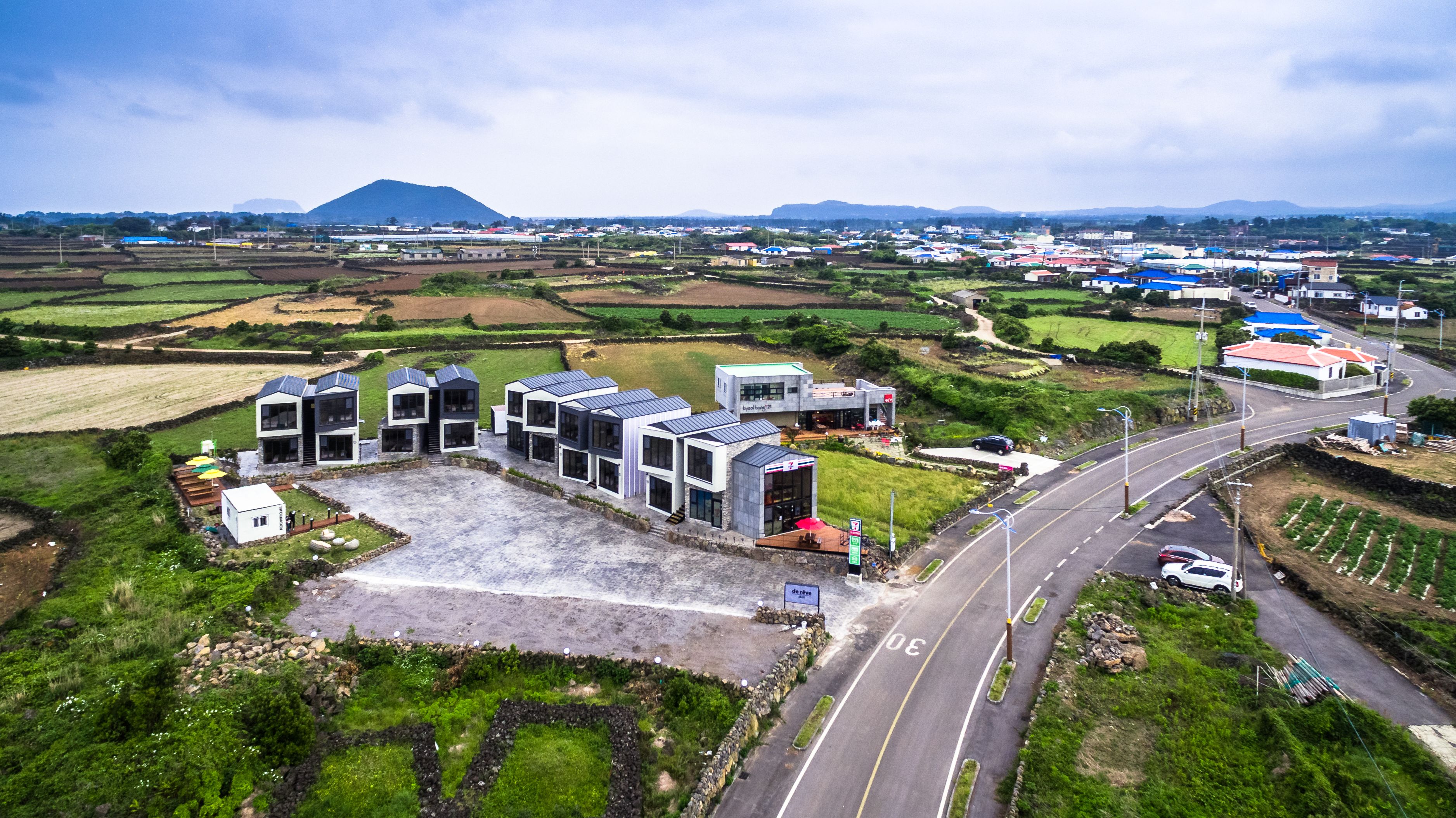 A modern building complex with multiple structures, a central courtyard, and a road leading to a bridge.