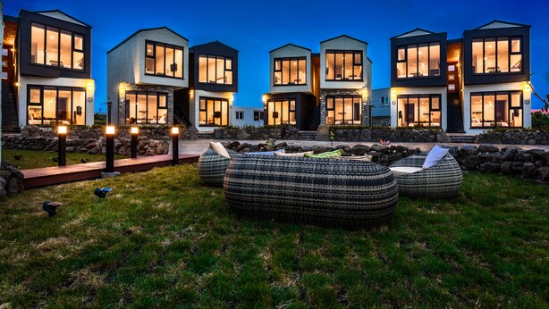 Een modern wooncomplex met meerdere huizen, buiten zitgedeeltes en een verzorgd gazon.