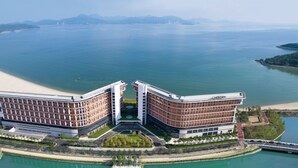 Un hotel moderno con fachada curva, situado cerca de una playa y una masa de agua.
