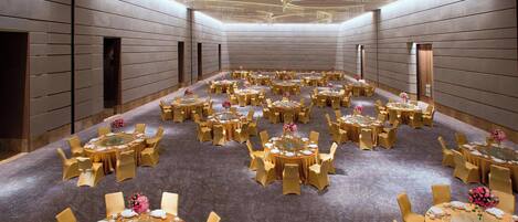 Une grande salle de banquet avec de nombreuses tables rondes, chacune étant agrémentée de chaises et d’un centre de table.