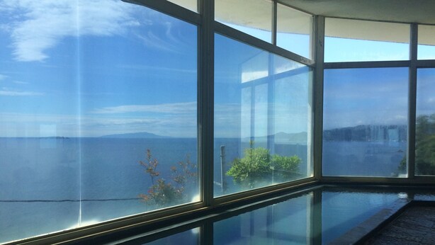A room with large windows offering a view of the sea and distant mountains. - Breezbay Seaside Resort Atami (Atami)