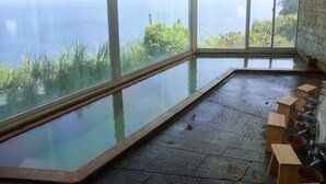 A spa room with a large window overlooking a body of water and greenery. - Breezbay Seaside Resort Atami (Atami)