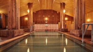 A wooden interior with a central pool, wooden walls, and a bench area. - Shintamagawa Onsen (Senboku)