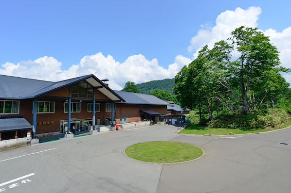 A building with a sloped roof, a covered entrance, and a paved area in front.
