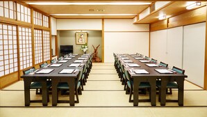 Een traditionele Japanse vergaderruimte met tatami matten, houten tafels en stoelen die voor een vergadering zijn gezet.
