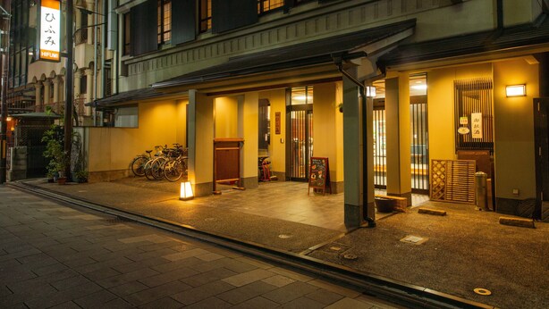 Een traditioneel Japans gebouw met een overdekte ingang, fietsen die er geparkeerd staan en een bord dat een restaurant aangeeft.