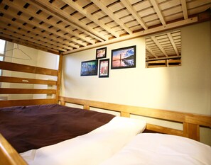 A single bed with a wooden headboard and a slatted ceiling. - Osaka Guesthouse Nest - Hostel (Osaka)