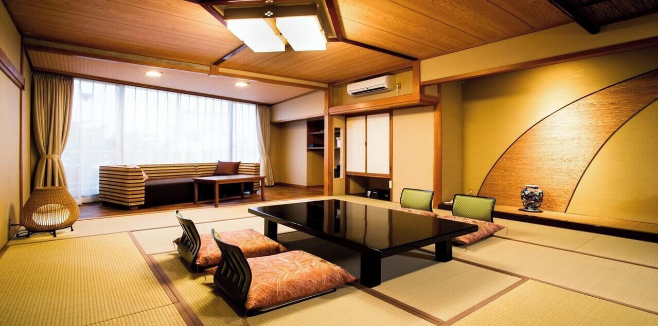 Una habitación tradicional japonesa con suelo de tatami, una mesita baja, cojines y puertas correderas.