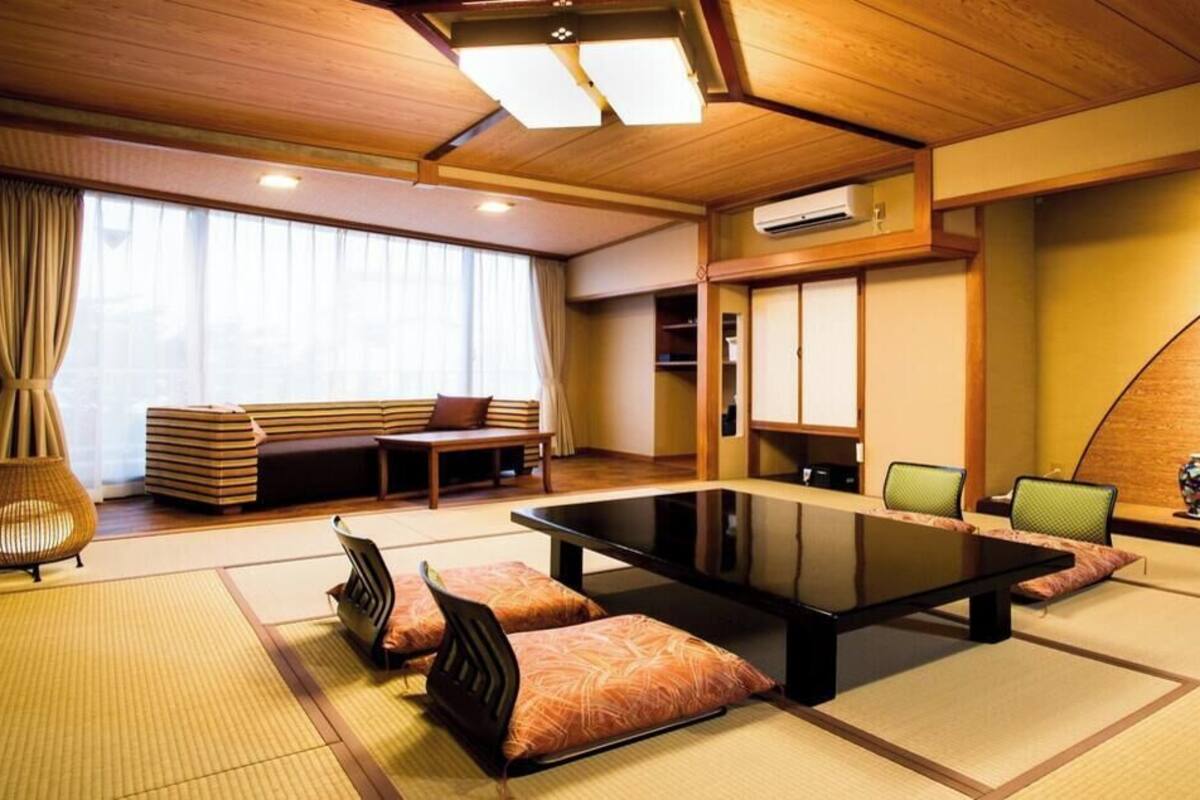 Una habitación tradicional japonesa con suelo de tatami, una mesita baja, cojines y puertas correderas.