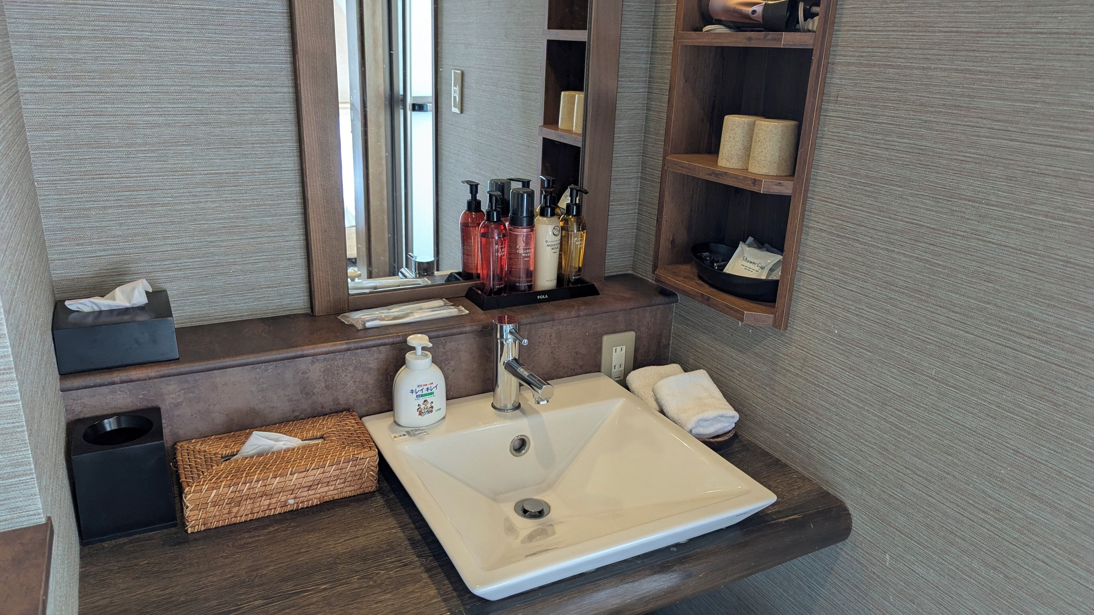 Un bagno con un lavandino capiente, uno specchio e ripiani con articoli da toilette.