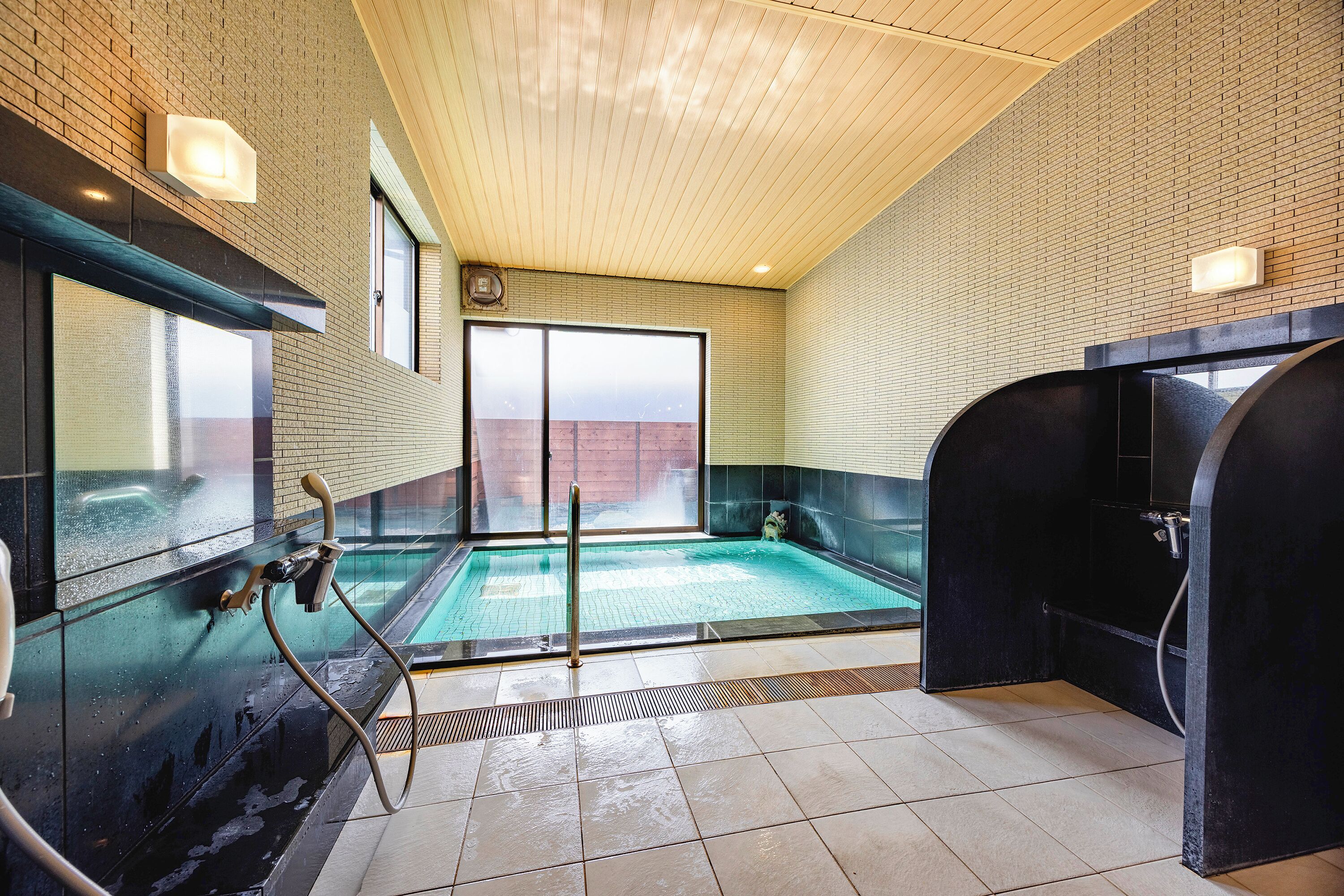A spa area with a large window, a hot tub, and a shower area.