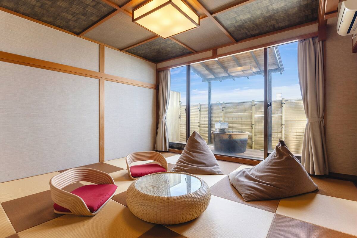 Una habitación japonesa tradicional con suelo de tatami, una mesa de madera baja y cojines.