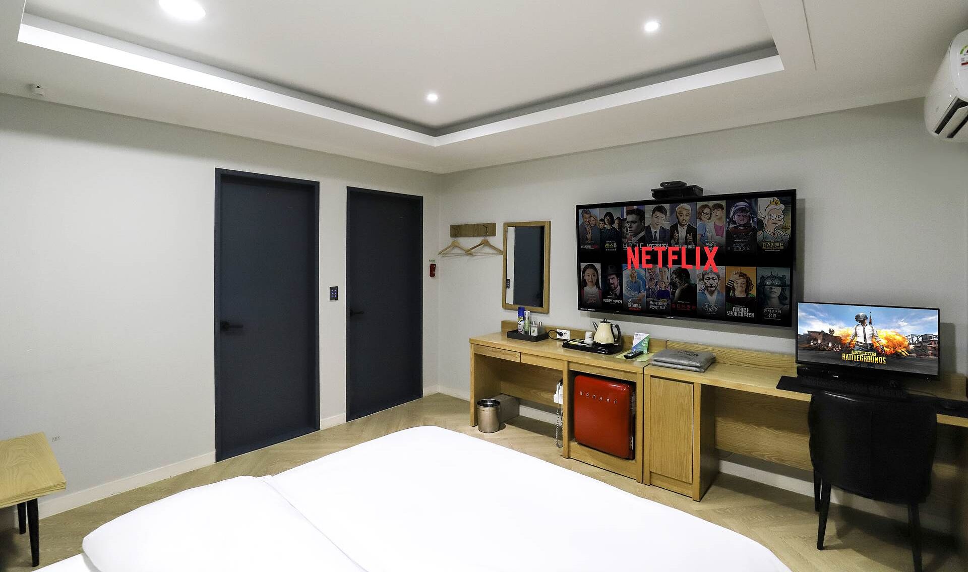 Une chambre d’hôtel équipée d’un lit, d’un bureau avec un ordinateur, d’une télévision et d’un mini-bar.
