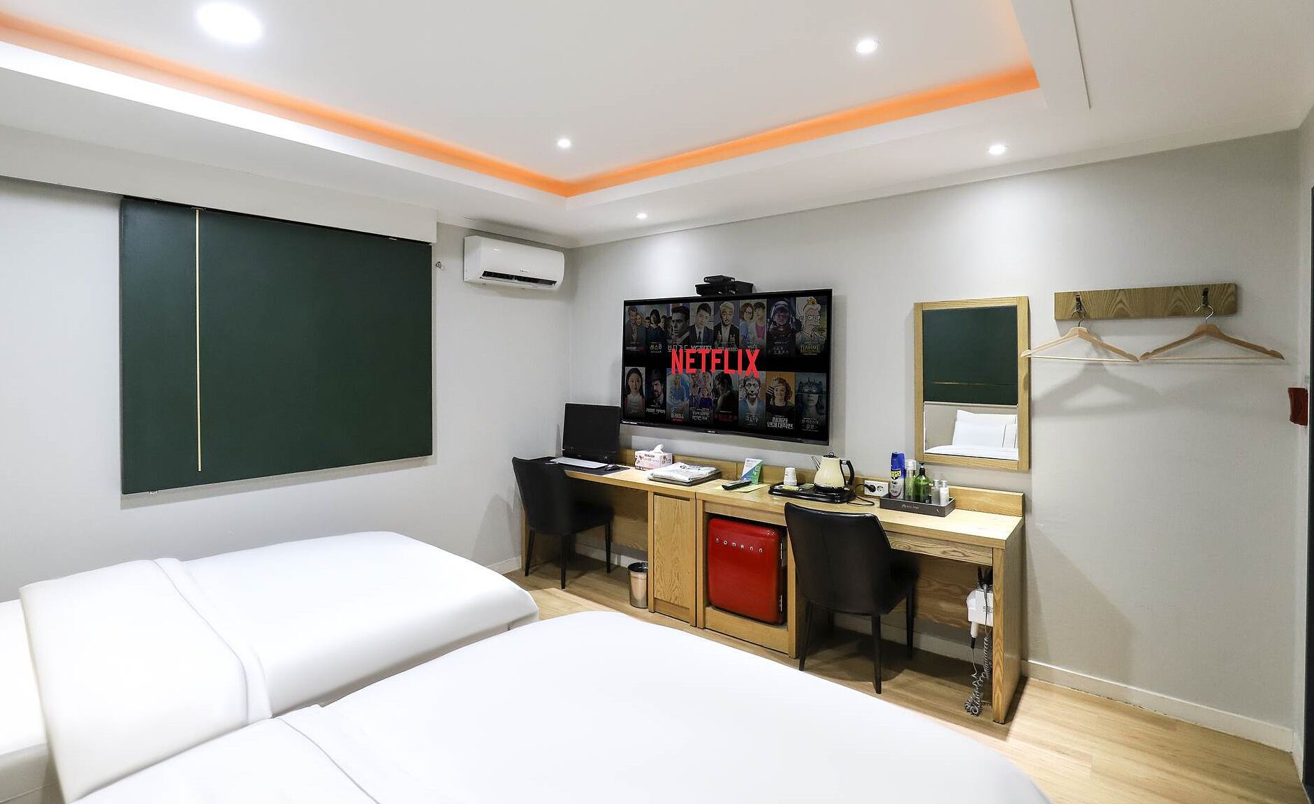 A hotel room with a bed, a desk with a computer, a TV, and a mirror.