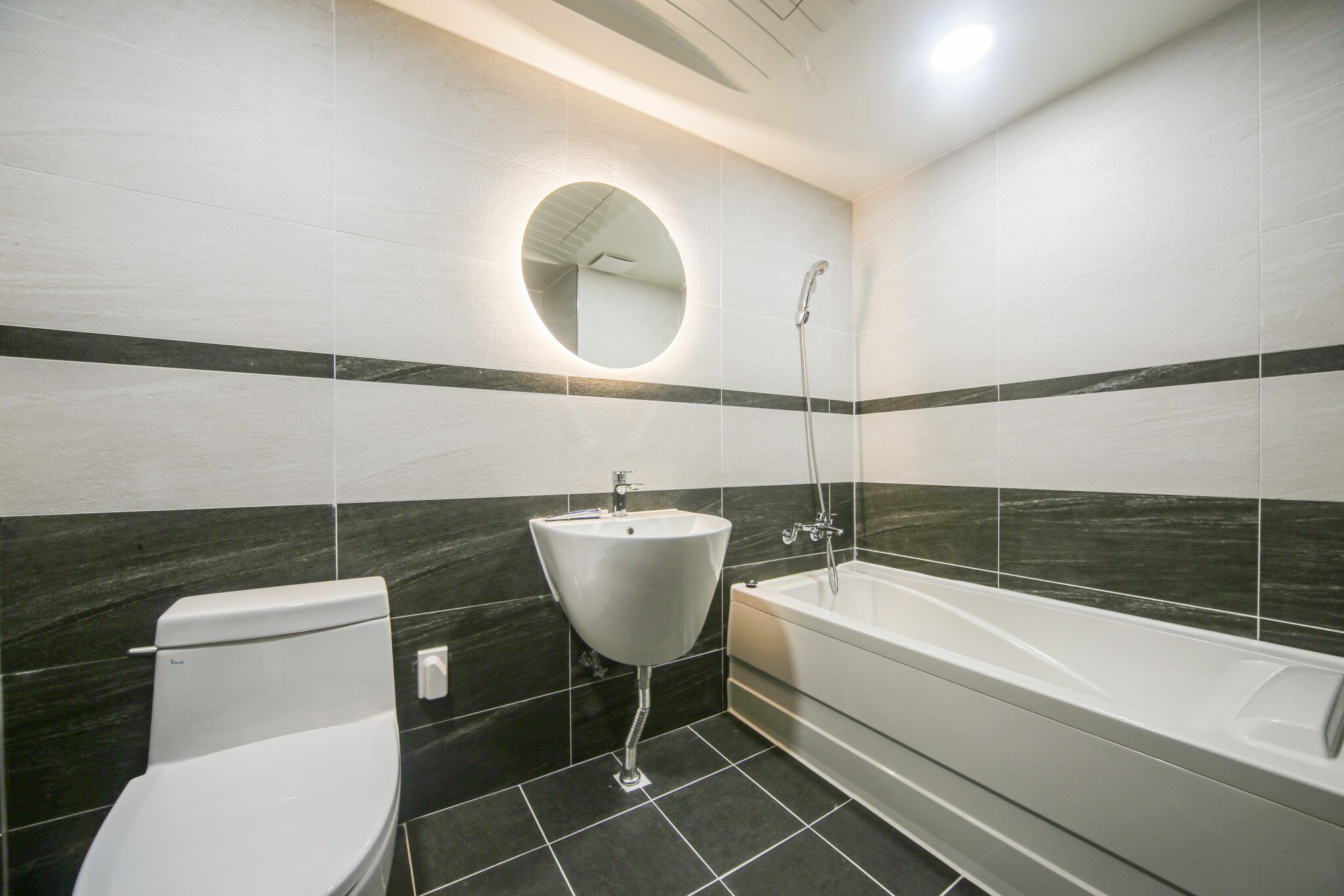 A modern bathroom with a toilet, sink, and bathtub.