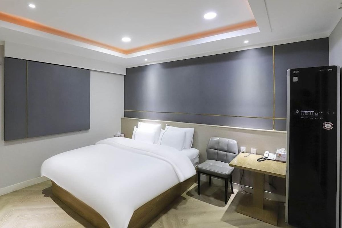 A modern hotel room with a large bed, a desk, and a seating area.