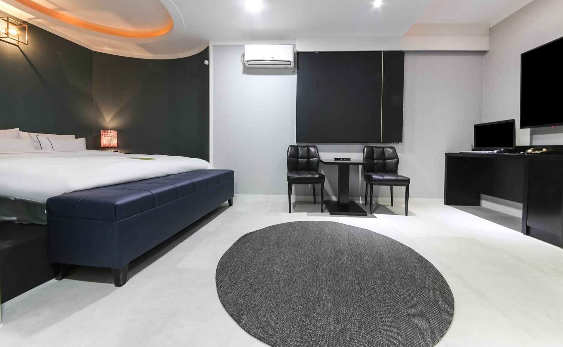 Une chambre d’hôtel moderne dotée d’un grand lit, d’un bureau avec deux chaises, d’un téléviseur à écran plat et d’un appareil de climatisation.