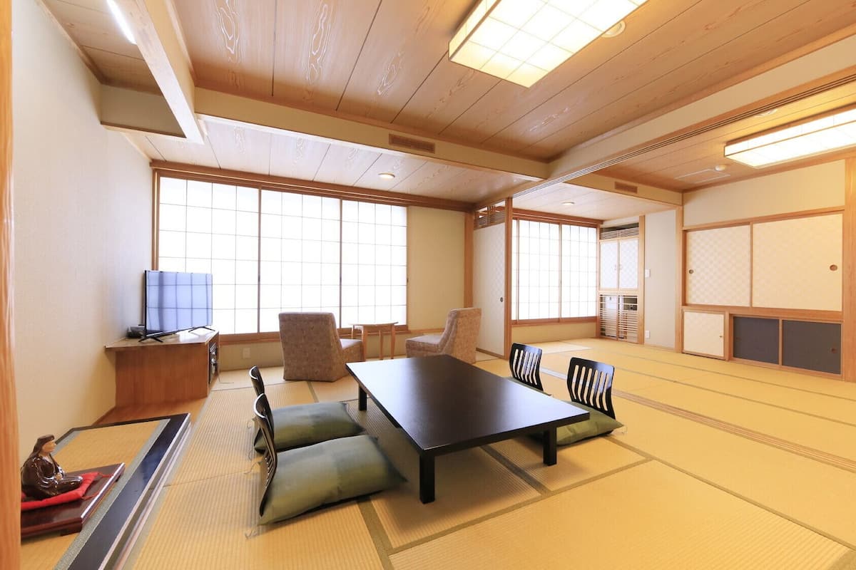 Una habitación japonesa tradicional con suelo de tatami, una mesa baja y puertas correderas.