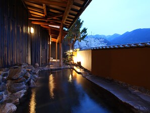A traditional Japanese-style building with a stone pathway leading to a small pond, surrounded by wooden walls and a tiled roof. - Ryokan Biyunoyado (Yamanouchi)