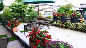 Une terrasse avec des meubles d’extérieur, des plantes en pot et une table en bois.