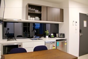 A compact kitchen with a built-in microwave, a sink, and a dishwasher. There is a small dining area with a table and chairs.