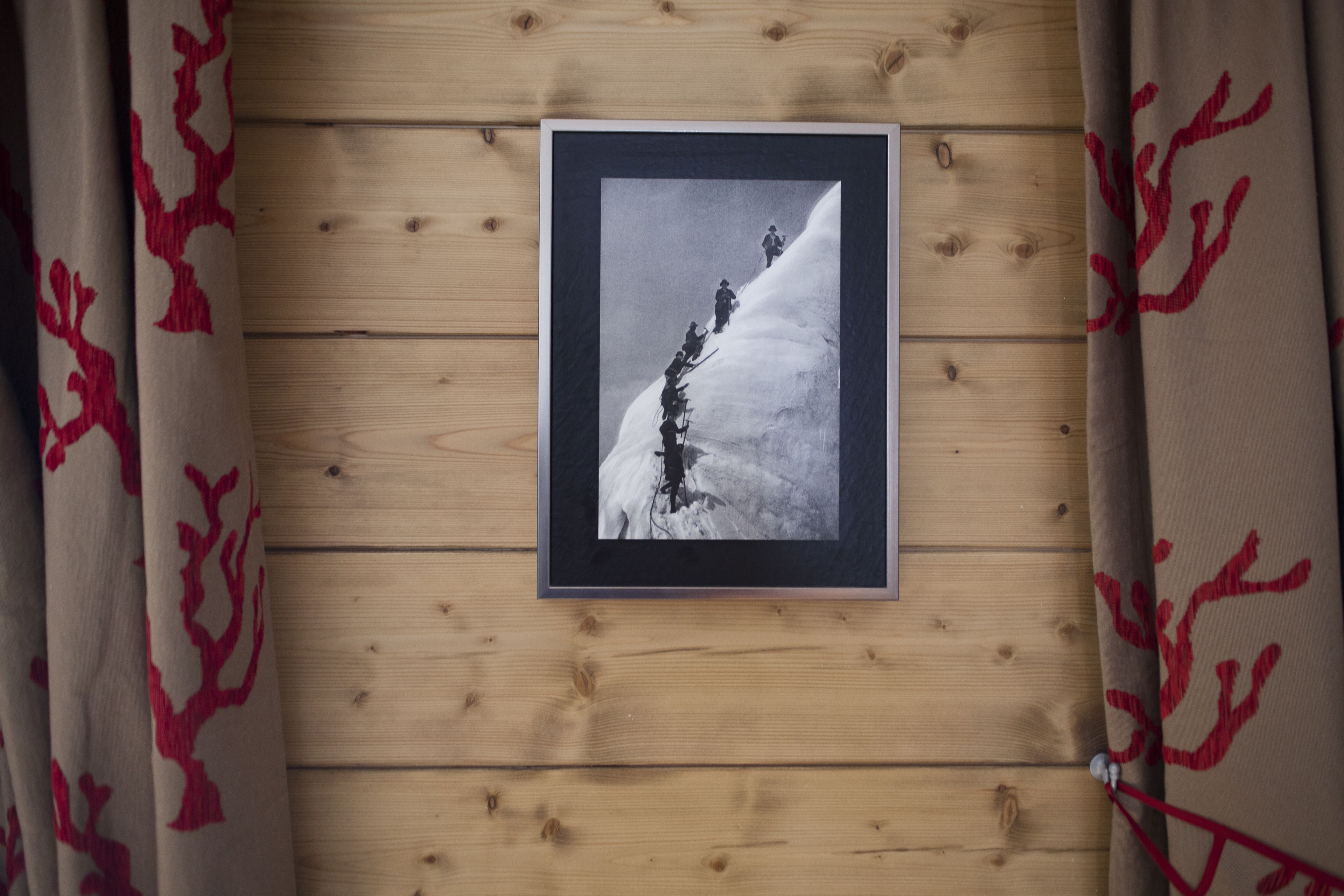 Une photographie encadrée représentant un paysage de montagne enneigé, accrochée à un mur en bois.