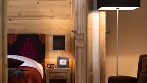 Quarto com painéis de madeira, uma cama, uma mesa de cabeceira, um abajur e uma cadeira.