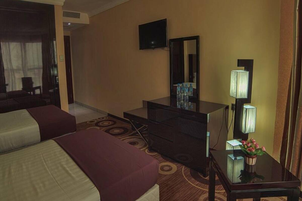 Ein Hotelzimmer mit einem Bett, einem Schreibtisch mit Spiegel, einem Fernseher und einer Lampe.