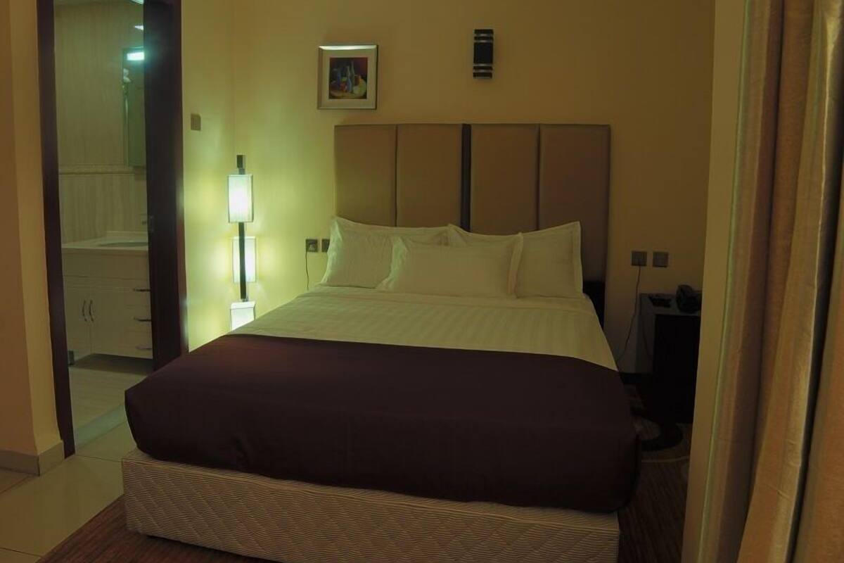 Ein Hotelzimmer mit einem großen Bett, einer Nachttischlampe und einem Bild an der Wand.
