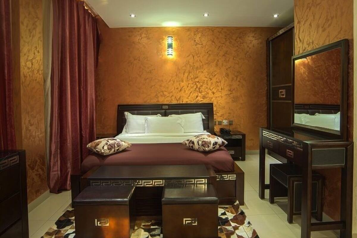 Ein Schlafzimmer mit einem Bett, Nachttischen, einem Spiegel und einem gemusterten Teppich.