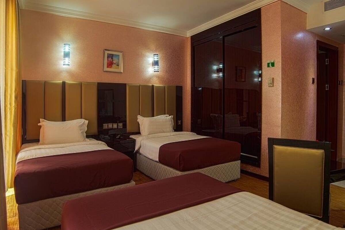Ein Hotelzimmer mit zwei Betten, einem großen Spiegel und einer Schiebetür zu einem Badezimmer.