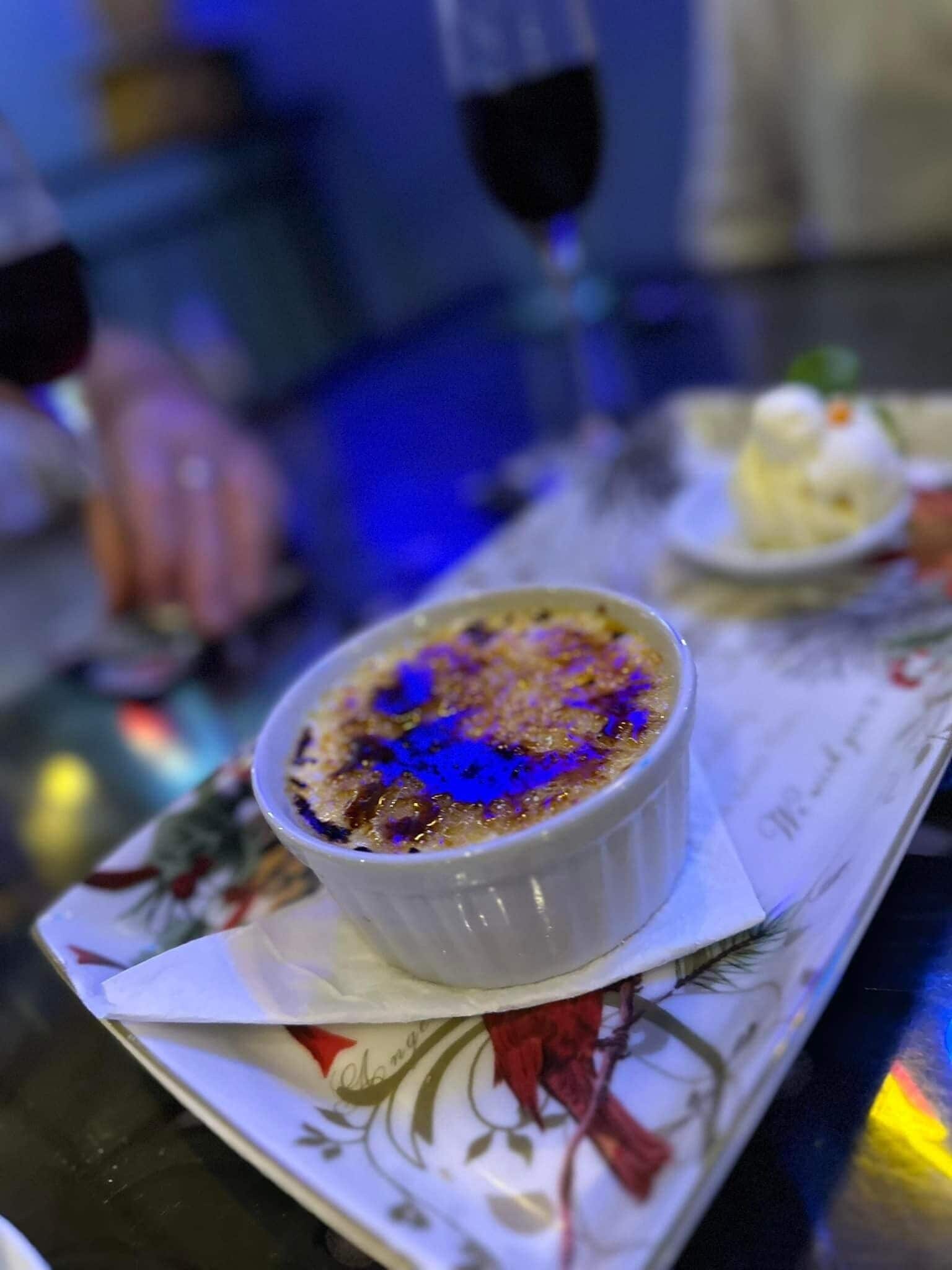 Un postre en un tazón blanco sobre una mesa con servilleta estampada con flores.